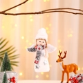 Close-up of white plush Christmas angel ornament with silver stars hanging on a branch - Grey Angel