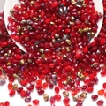 Macro shot of 6x8mm teardrop faceted red glass beads spilling out of a white ceramic bowl - Red Series