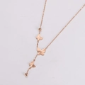 Dettaglio macro della collana oro rosa con tre ciondoli a farfalla e perline metalliche - Oro rosa