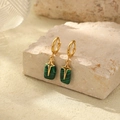 Close-up of gold hoop earrings with green rectangular pendants and cross engraving - Green Flat Round