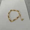 Golden bracelet with pink evil eye charms and brown rectangle stones on a soft fabric - Amber Yellow