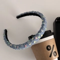 Detail van blauwe denim haarband met pailletten leunend tegen een witte koffiemok - Blauw