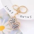 Close-up of golden heart keychain with white rhinestones and gray crystal flowers - White Rhinestone Grey Flower Heart