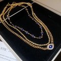 Nahaufnahme der goldenen Evil Eye Halsketten mit blauer Emaille und funkelnden Kristallen - 3-teiliges Set / Gold
