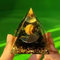 Hand holding crystal pyramid with yellow sphere, tree of life, and black crushed stones - Style 10