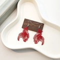 Détail de boucles d'oreilles poisson rouge ajourées style chinois sur plateau céramique - Rouge