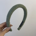 Close-up of green wool texture headband with a handmade label and padded design - Woolen Headband / Grass Green