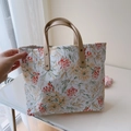 Dettaglio della borsa tote floreale con manico in pelle marrone e rivetti in metallo - Ramo di Fiori Arancio Rosso
