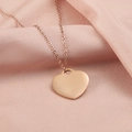 Primer plano de un colgante de corazón de oro rosa pulido en una cadena fina de seda - Oro Rosa