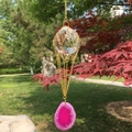 Gros plan d'une boule de cristal et tranche d'agate rose suspendue dans un jardin d'automne - Rose Rouge