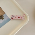 Close-up of a cute pink spotted cat hair clip on a minimalist white tray background - Pink