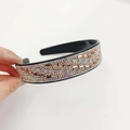 Sparkling champagne rhinestone headband with black base shown in hand on white background - Champagne Crystal Champagne