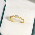 Detail eines wellenförmigen Goldrings mit Zirkon-Stein in einer grünen Schmuckbox - Wellenband Vier-Krappen Zirkon Stil (Gold 9)