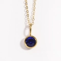 Close-up of a gold necklace with a round blue birthstone pendant on a white background - September Sapphire