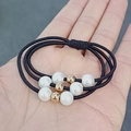 Three-strand black elastic hair tie with white pearls and gold beads on a hand - Solid Black