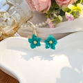 Detail of layered turquoise flower earrings on a ceramic tray with pearls and decor - Green
