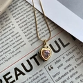 Detalle de un collar de titanio dorado con colgante de corazón rosa y microcircones - Rosa