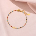 Close-up of gold stainless steel bracelet with colorful beads and a cross charm - Gold-Multicolor
