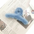 Blue plush faux fur hair claw clip for women on newspaper background for autumn and winter - Blue