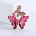 Dettaglio di spilla a farfalla dorata con cristalli rosa e strass luccicanti - Rosa