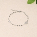 Close-up of silver beaded bracelet with religious cross and Mary medallion on beige texture - Silver Steel Maria