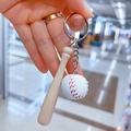 Detalle de un llavero deportivo con mini pelota de béisbol de cuero y bate de madera - Bate Largo 7.5CM/Pelota Blanca