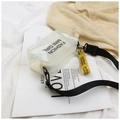 Dettaglio di una mini borsa trasparente in PVC con tracolla nera e ciondolo giallo - Bianco avorio
