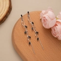 Macro shot of silver leaf tassel earrings with black gemstones on a wooden stand - Silver-Black Zirconia