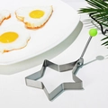 Star-shaped stainless steel egg mold with green handle on a white ceramic plate - Pentagram
