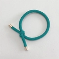 Detail of dark green woven elastic hair tie with textured knot and gold metal cylinders - Green