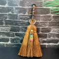 Macro detail of brown witch broom with chakra stones, moon pendant and aura quartz - Obsidian + Moon + Trichroic Crystal