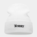 Close-up van zwart 'Mommy' borduursel op een witte gebreide muts met een omslag - Mommy Borduurwerk / Wit