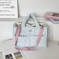Détail du sac fourre-tout matelassé bleu clair avec bandoulière rose et texture en tissu souple - Bleu clair