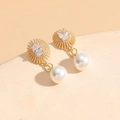 Elegant gold drop earrings with oval zircon studs and white pearls on a beige display - Gold Sun Zircon Pearl