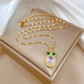 Detailopname van gouden uil-ketting met groene edelstenen ogen en heldere kristallen - Uil Stijl (G129)