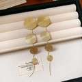 Golden multi-disc tassel earrings with textured finish on a beige velvet jewelry box - Gold
