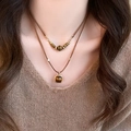 Close-up of a double-layered tiger eye pendant necklace on a brown cord with gold beads - Double Layer Brown Cord Choker (21#)