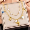 Collar de doble capa en oro con colgantes de estrella de mar y concha sobre satén - Delfín
