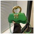 Detail einer grünen Wellenhandtasche mit goldenem Metallgriff und Schleife - Grün