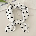 White linen scarf with black heart pattern styled as a bow on a desktop - White Heart