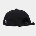 Close-up of black cotton brimless cap with white m embroidery and bronze metal adjustment buckle - Adjustable / Black