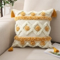 Dettaglio federa cuscino bohémien con nappe gialle posizionato su divano beige - Tufted Pois Giallo Bianco