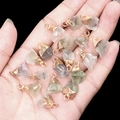 Irregular natural semi-precious stone pendants with gold-plated caps held in palm - Fluorite