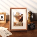 Solid walnut wood photo frame with white matting displayed on a wooden table - Pear Wood