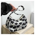 Detail of a stylish black and white heart print baguette bag held against a white wall - Heart