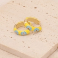 Close-up of yellow enamel daisy hoop earrings on a textured stone surface - Yellow