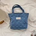 Close-up of blue denim tote bag featuring white heart and bow patterns on textured fabric - Dark Blue