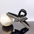 Close-up of elegant black bow hair claw clip with rhinestones on a reflective surface - Transparent Grey Rhinestone
