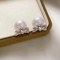Detalle de pendientes de lazo chapados en oro 18K con perlas brillantes sobre seda - Plateado con perla blanca