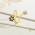 Detailed close-up of a golden daisy ring with enamel petals and a sparkling zircon stone - Adjustable Open / Black Flower